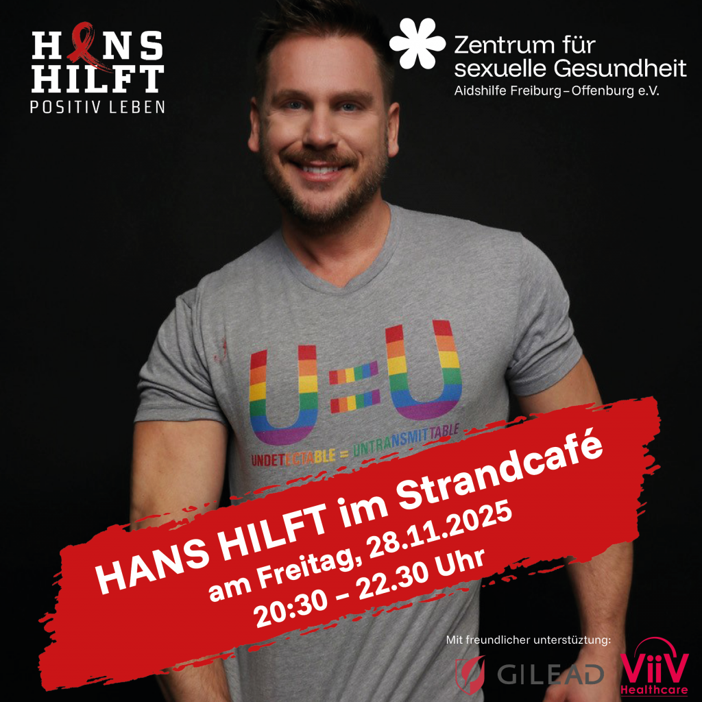 Hans Berlin lächelt in die Kamera. Er ist nur mit einem T-Shirt begleitet und zieht es nach unten um seinen Genitalbereich zu verdecken.