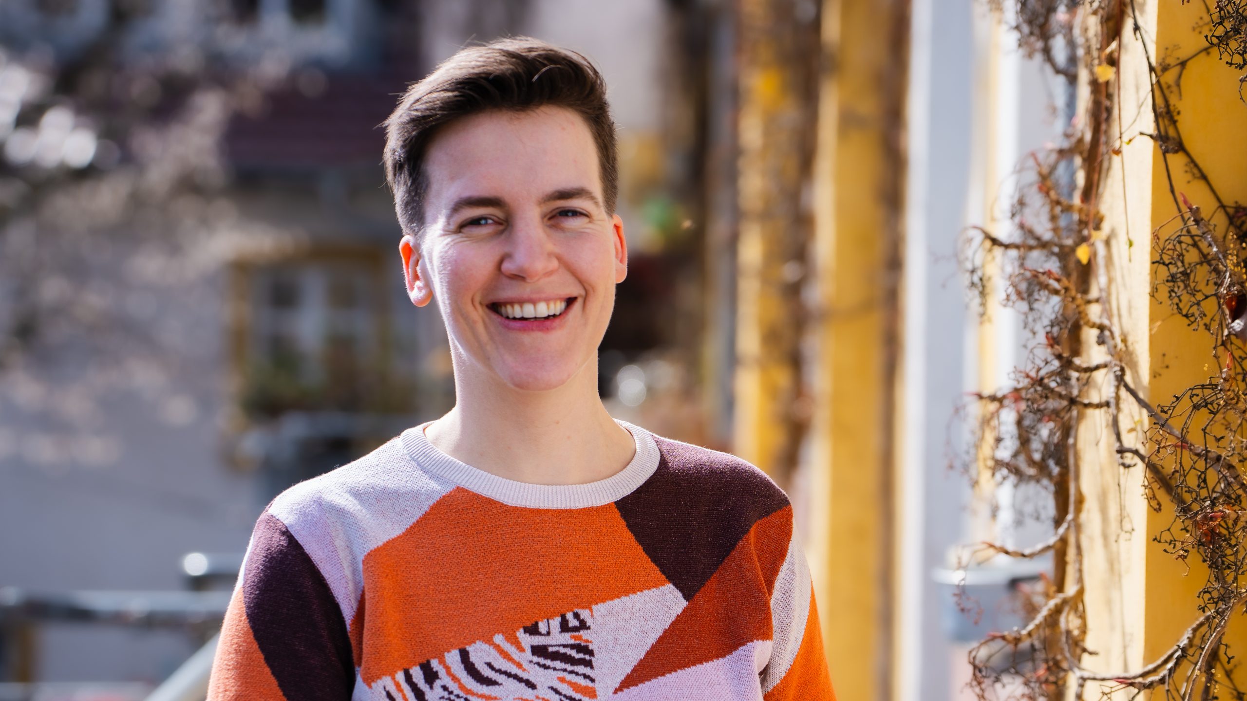Rebecca steht im Hof der Rosa Hilfe und lacht in die Kamera